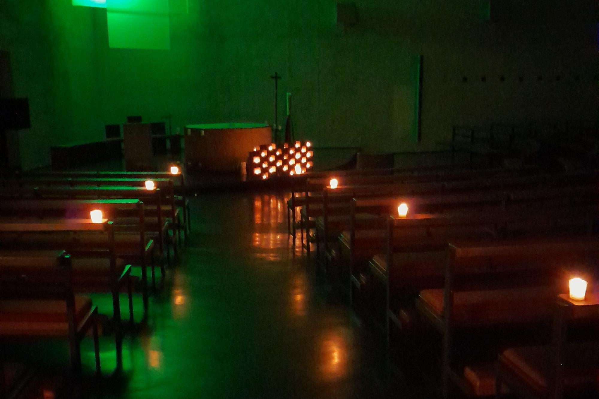 beleuchtetes Kreuz, Kirche bei Kerzenschein